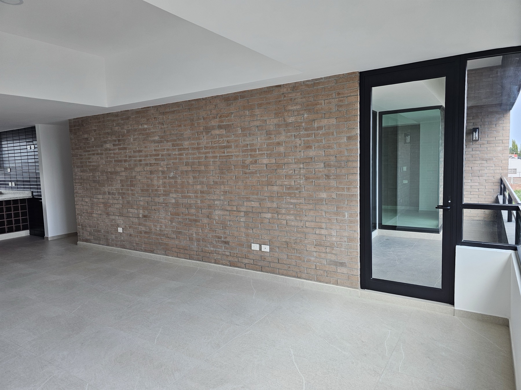 Estancia con muro de ladrillo y puerta hacia el balcón